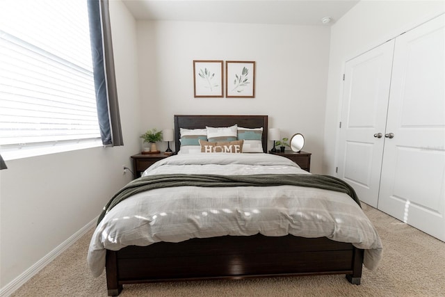 bedroom featuring baseboards, light colored carpet, and a closet