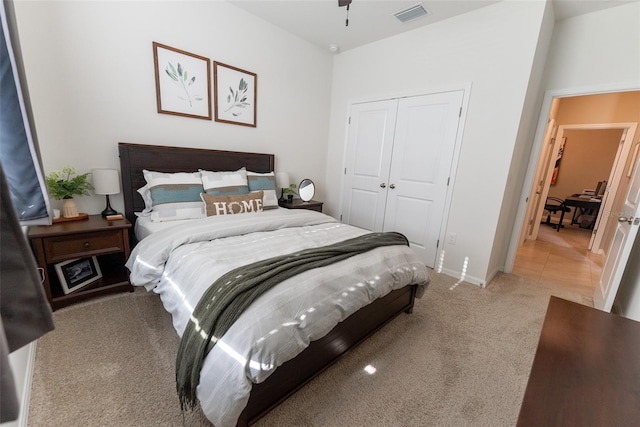bedroom with a closet, baseboards, light colored carpet, and visible vents