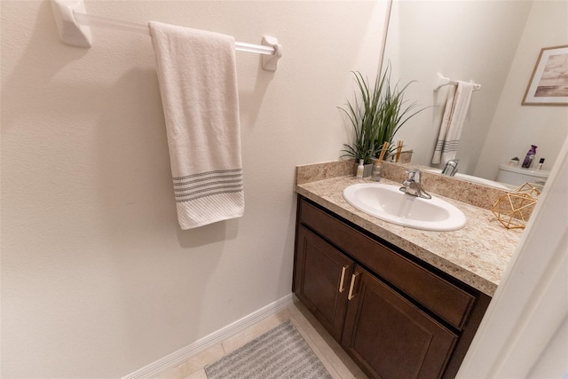 half bathroom with vanity, baseboards, and tile patterned floors