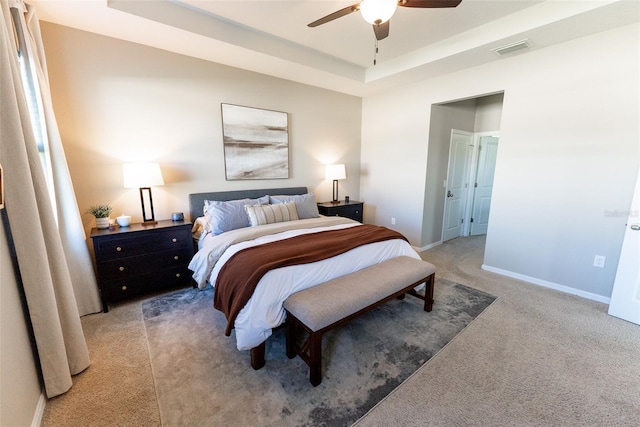 bedroom with ceiling fan, light colored carpet, a raised ceiling, baseboards, and visible vents