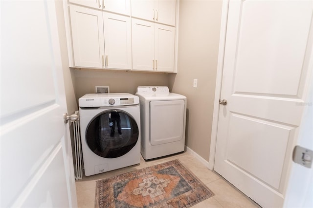 laundry room featuring light tile patterned floors, separate washer and dryer, baseboards, and cabinet space