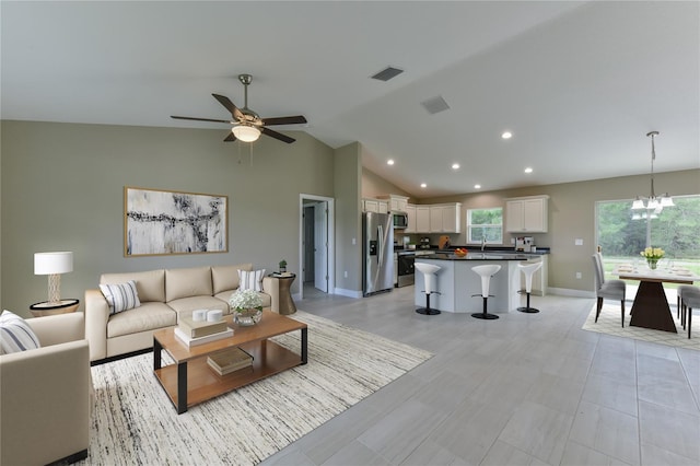 living area featuring high vaulted ceiling, ceiling fan with notable chandelier, recessed lighting, baseboards, and visible vents
