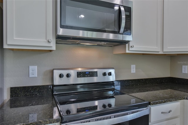 kitchen with dark stone counters, stainless steel appliances, and white cabinetry