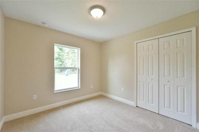 unfurnished bedroom with a closet, baseboards, and carpet flooring