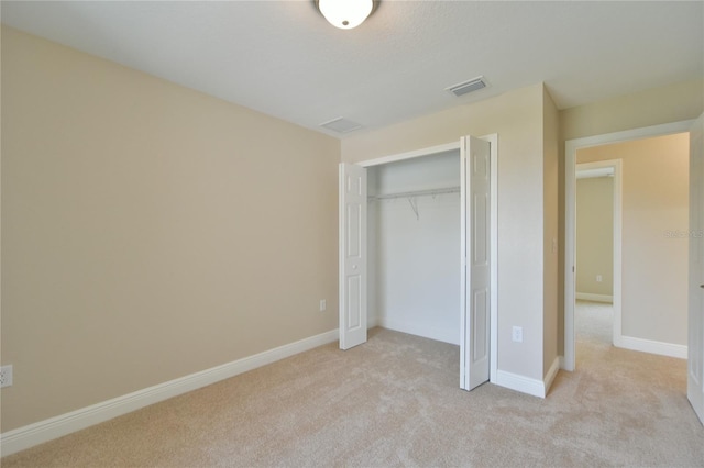 unfurnished bedroom with visible vents, baseboards, a closet, and light carpet