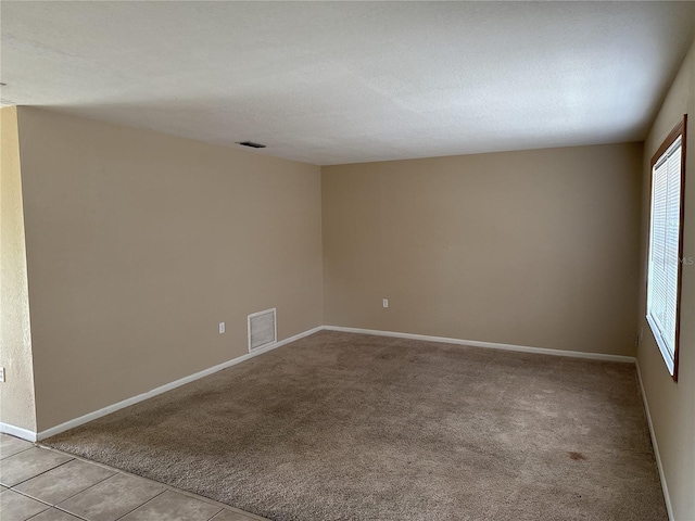 unfurnished room with visible vents, baseboards, and light colored carpet