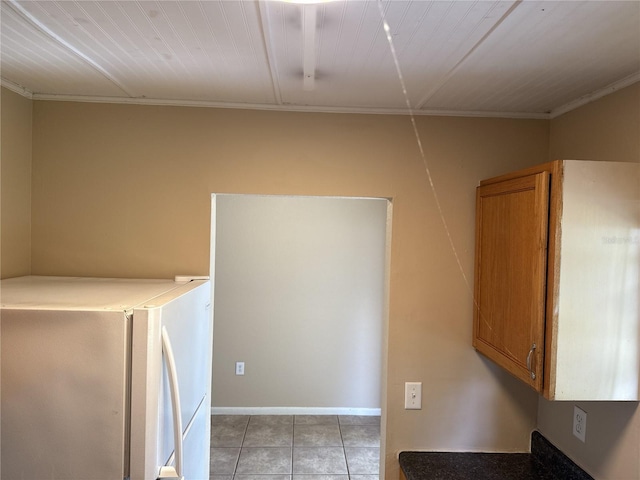 clothes washing area with crown molding, baseboards, and light tile patterned floors