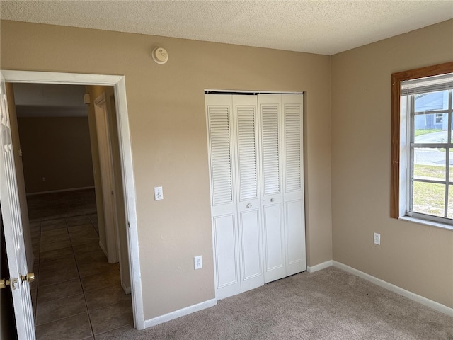unfurnished bedroom featuring a textured ceiling, baseboards, and a closet