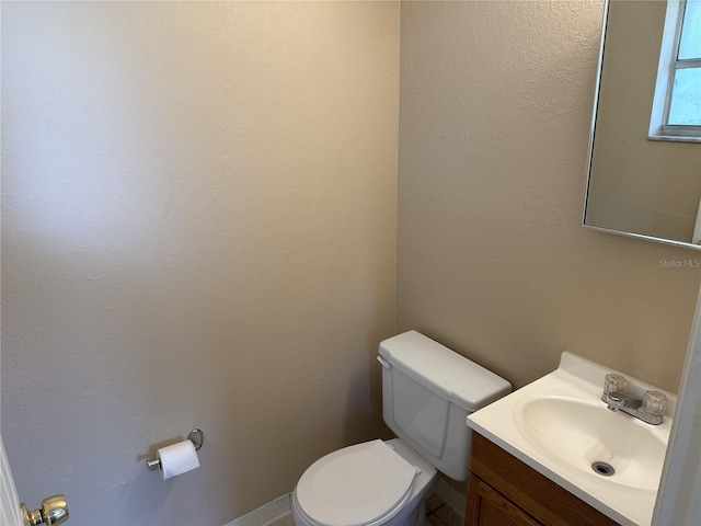 half bath featuring vanity and toilet