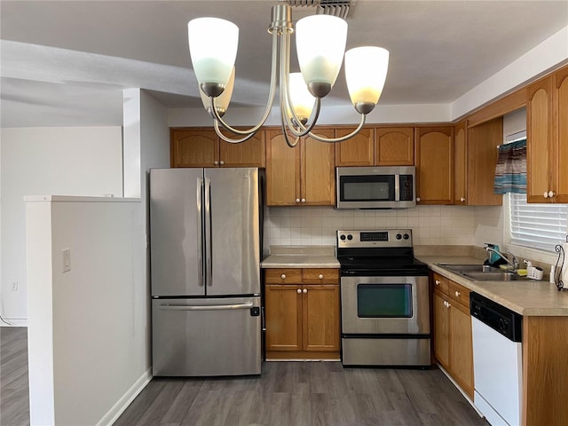 kitchen featuring appliances with stainless steel finishes, an inviting chandelier, a sink, light countertops, and dark wood finished floors