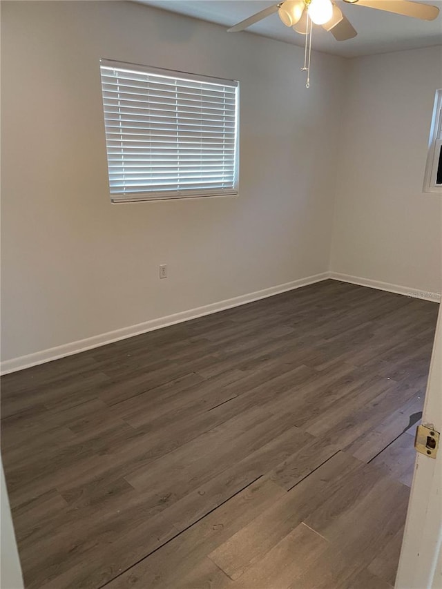spare room featuring baseboards, a ceiling fan, and dark wood-type flooring