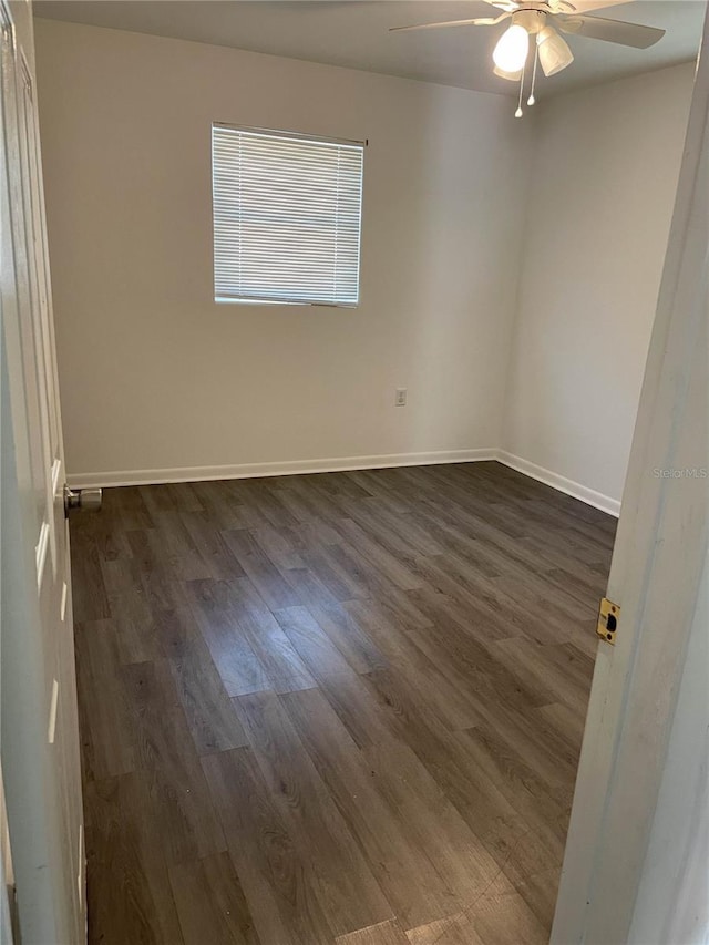 unfurnished room featuring ceiling fan, dark wood finished floors, and baseboards