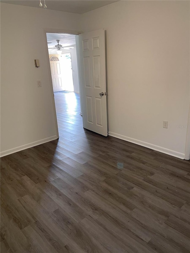 spare room with baseboards and dark wood finished floors