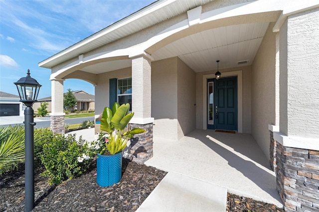 7706 SW 89th Ct, Ocala, FL 34481 - entrance to property featuring covered porch, stucco siding, visible vents, and stone siding