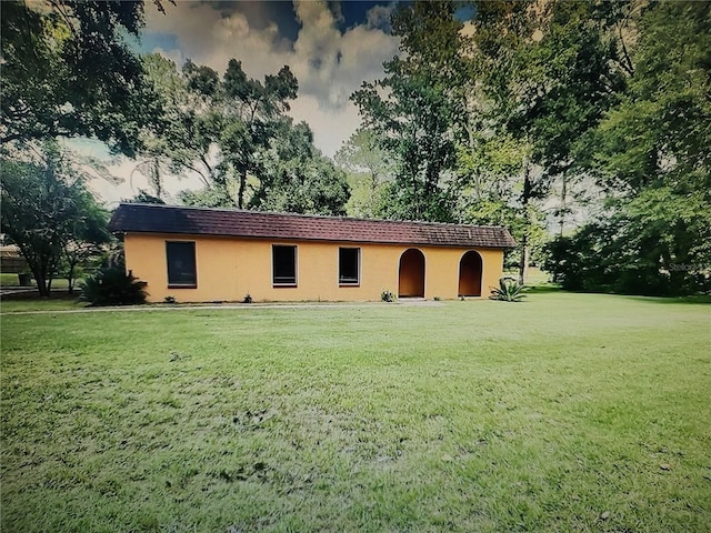 back of property with a lawn and stucco siding