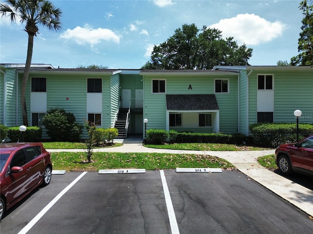 view of property featuring stairs and uncovered parking