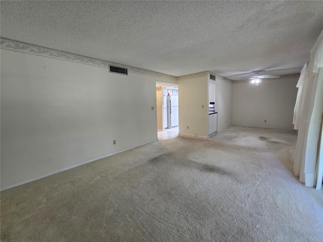 unfurnished room with baseboards, light carpet, a textured ceiling, and visible vents