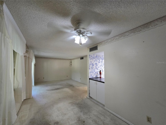 unfurnished room with a ceiling fan, a textured ceiling, visible vents, and light carpet