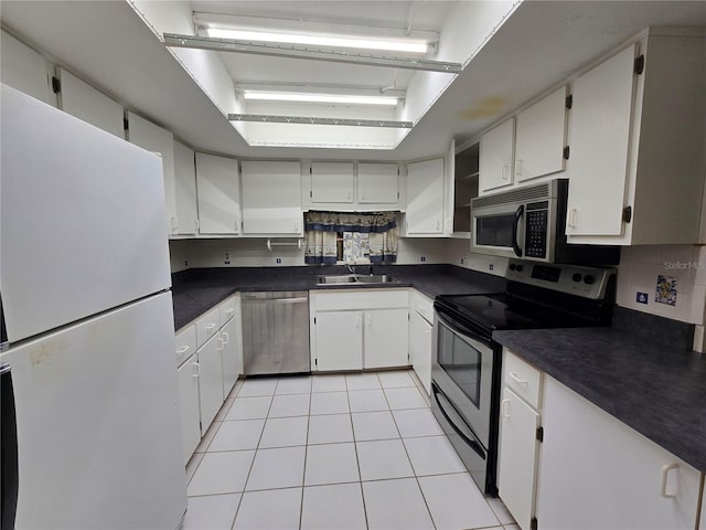 kitchen with a sink, dark countertops, light tile patterned floors, and stainless steel appliances
