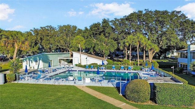 community pool featuring a lawn, fence, and a patio area