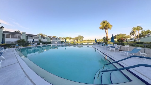 community pool with a patio area and fence