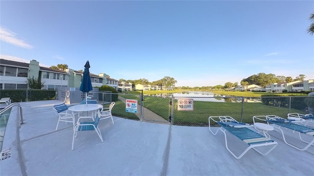 view of patio / terrace featuring fence, a water view, and a residential view