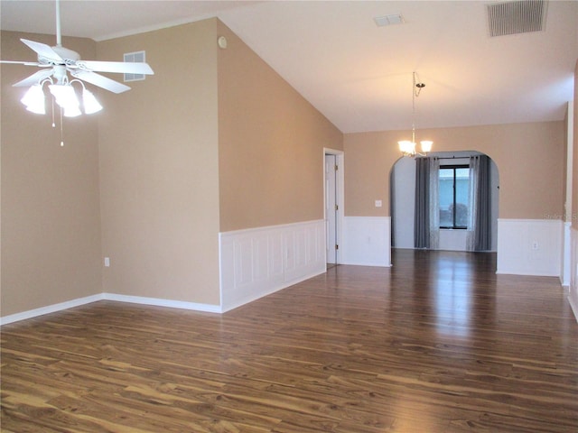 empty room featuring arched walkways, dark wood-style flooring, ceiling fan, and wainscoting