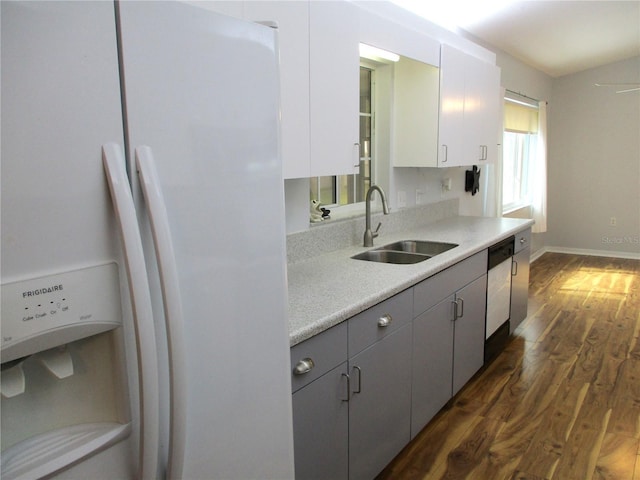 kitchen with light countertops, a sink, dark wood-style floors, dishwashing machine, and white fridge with ice dispenser