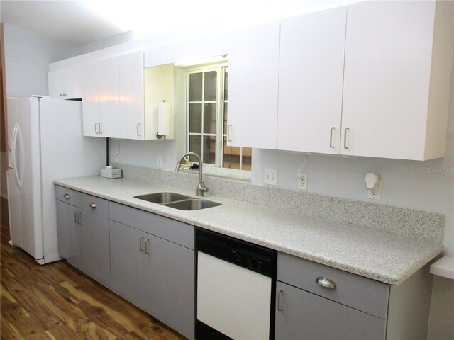 kitchen with dark wood-style flooring, a sink, light countertops, gray cabinetry, and white appliances