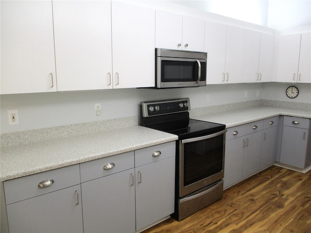 kitchen featuring gray cabinetry, light countertops, stainless steel appliances, and dark wood-type flooring
