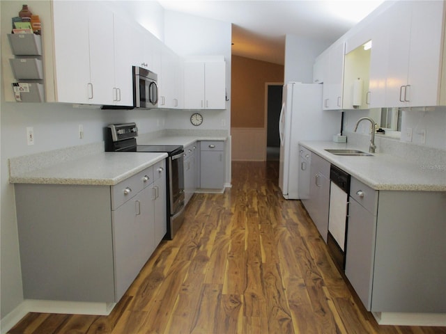 kitchen with wood finished floors, light countertops, white cabinets, a sink, and stainless steel appliances