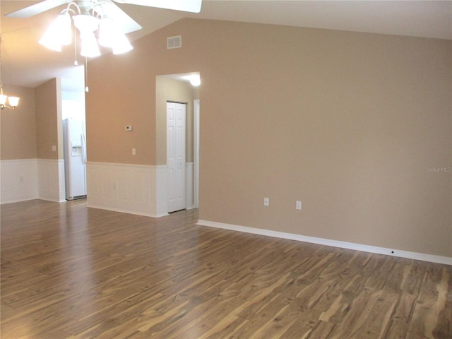unfurnished room with visible vents, wainscoting, dark wood finished floors, ceiling fan with notable chandelier, and lofted ceiling
