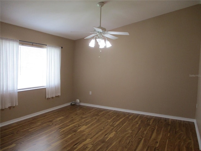 empty room with ceiling fan, baseboards, and dark wood-type flooring
