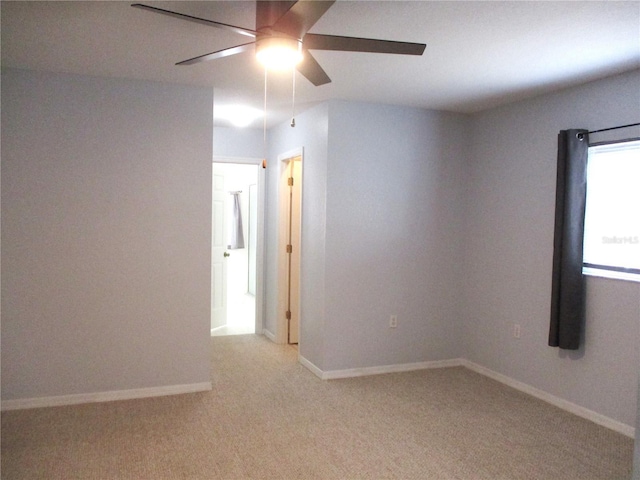 unfurnished room featuring baseboards, a ceiling fan, and light carpet