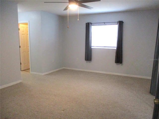 carpeted empty room featuring baseboards and a ceiling fan