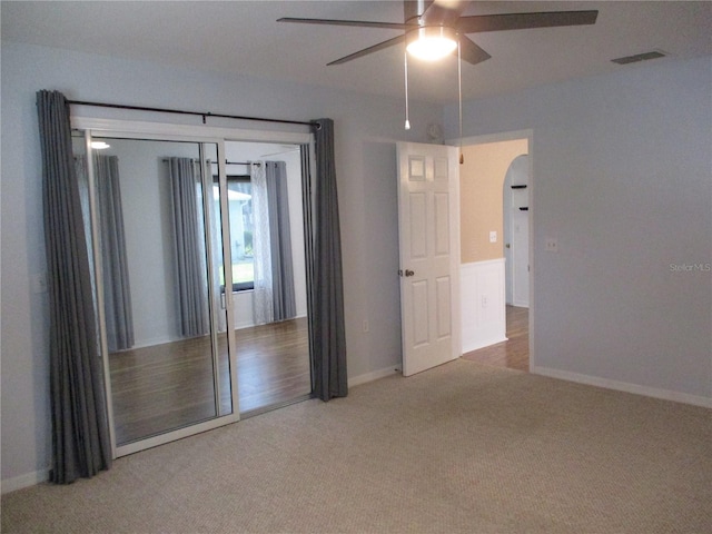 spare room with a ceiling fan, visible vents, arched walkways, baseboards, and carpet flooring