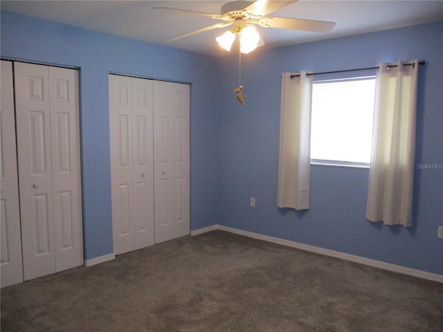unfurnished bedroom featuring carpet floors, multiple closets, ceiling fan, and baseboards
