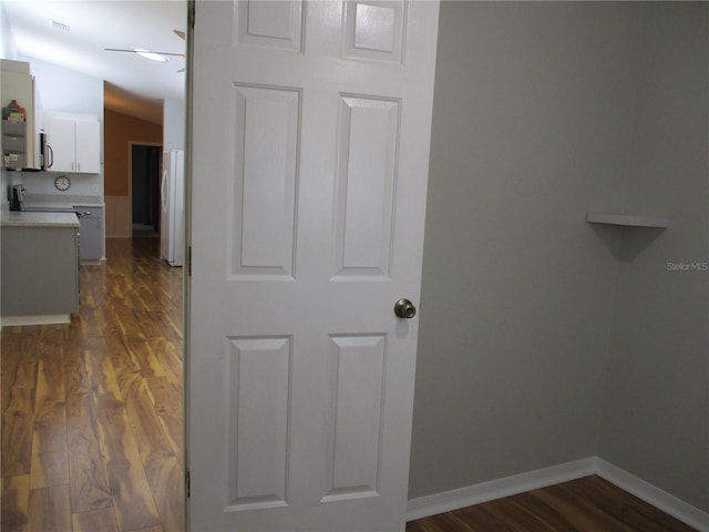 corridor featuring baseboards, visible vents, dark wood-style floors, and lofted ceiling