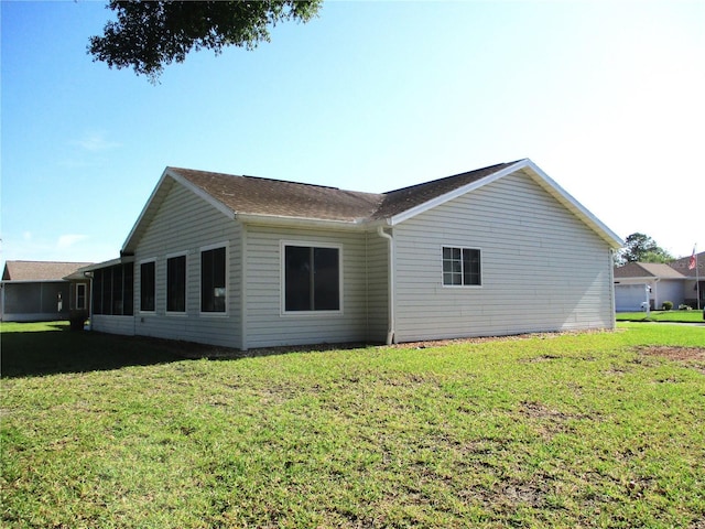 rear view of property with a lawn and roof with shingles