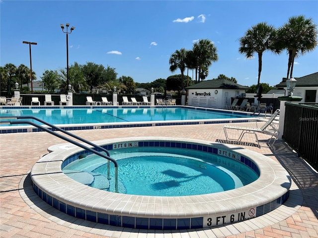 pool with a patio, fence, and a community hot tub