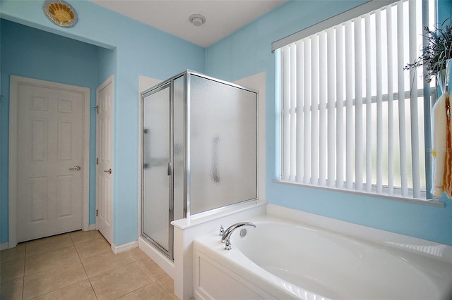 bathroom featuring tile patterned flooring, a bath, and a stall shower