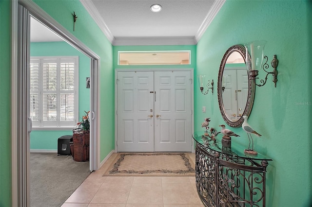tiled foyer entrance featuring baseboards, ornamental molding, and a textured ceiling