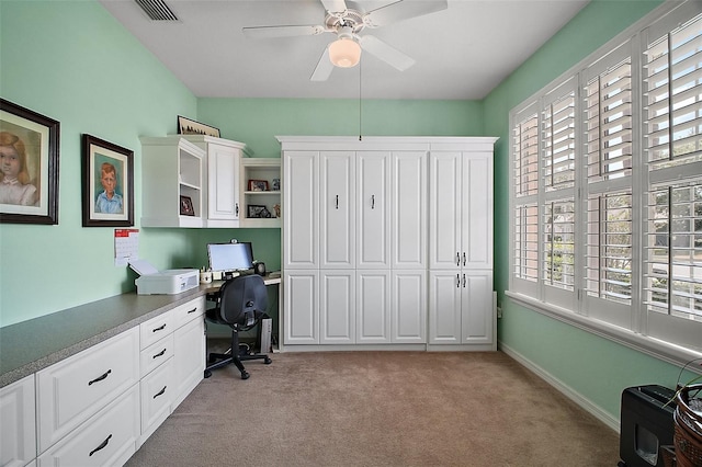 office space with ceiling fan, visible vents, light carpet, and built in study area