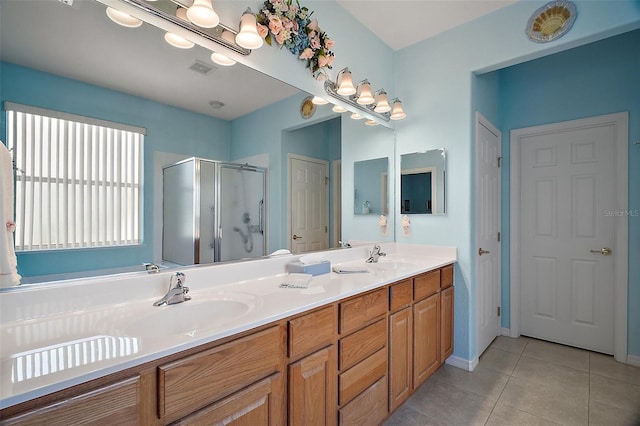 bathroom featuring double vanity, a sink, tile patterned flooring, and a stall shower