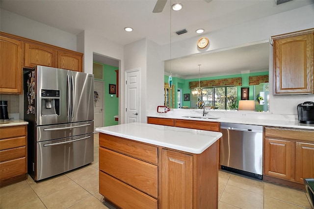 kitchen with brown cabinetry, a sink, appliances with stainless steel finishes, and light tile patterned flooring