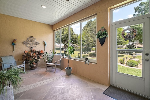 sunroom with plenty of natural light, stone tile floors, and a textured wall
