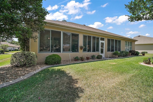 back of house with a lawn and stucco siding