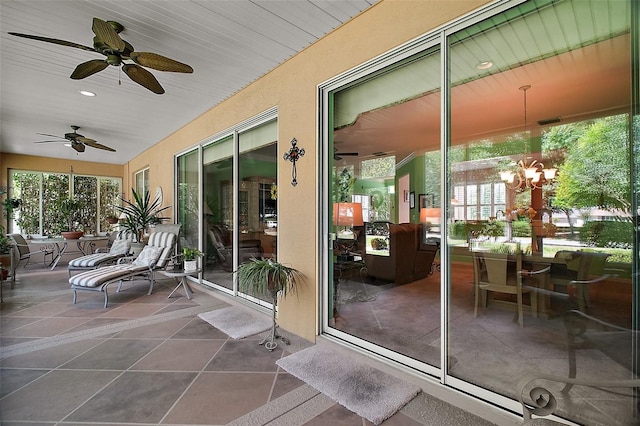 sunroom featuring ceiling fan with notable chandelier