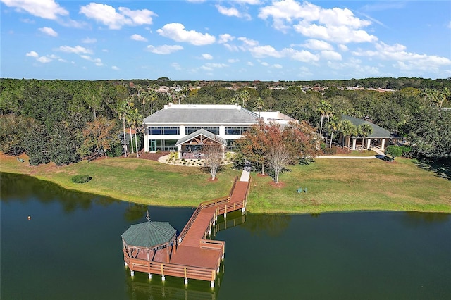 view of dock featuring a lawn, a view of trees, and a water view