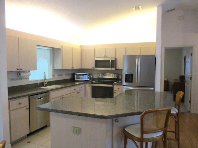 kitchen featuring visible vents, a toaster, a kitchen bar, a sink, and stainless steel appliances